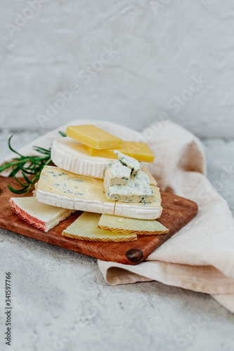 Different sorts of cheese, blue, brie, camembert and other with walnuts on wooden board background