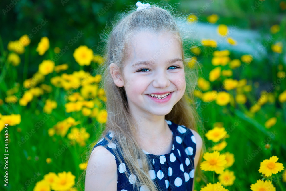 Little blonde girl with blue eyes among yellow flowers. Girl in a black dress in white peas. Baby walk . Girl in summer. Happy childhood, vacation.