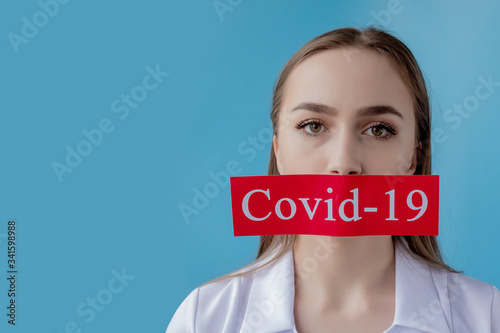 Doctor woman pointing to red paper with mesaage Coronavirus on blue background. World Health Organization WHO introduced new official name for Coronavirus disease named COVID-19