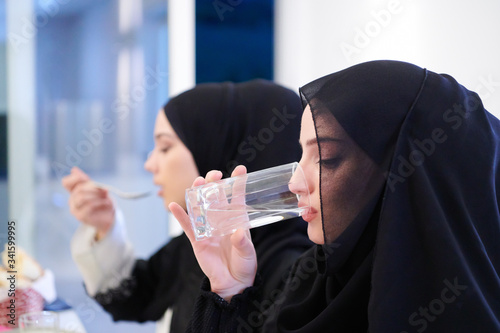 Sticker Muslim family having Iftar dinner drinking water to break feast
