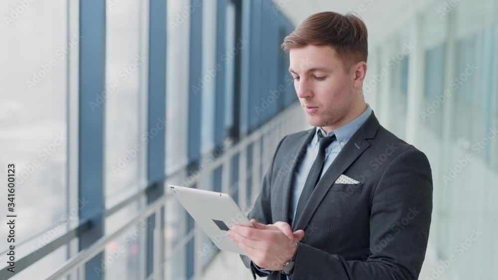 Business man in the hallway of business center looking at tablet Business man in the hallway of business center looking at tablet