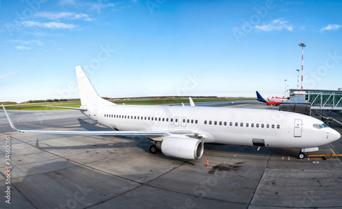 White passenger jet plane parked to a air bridge on a clear sunny day