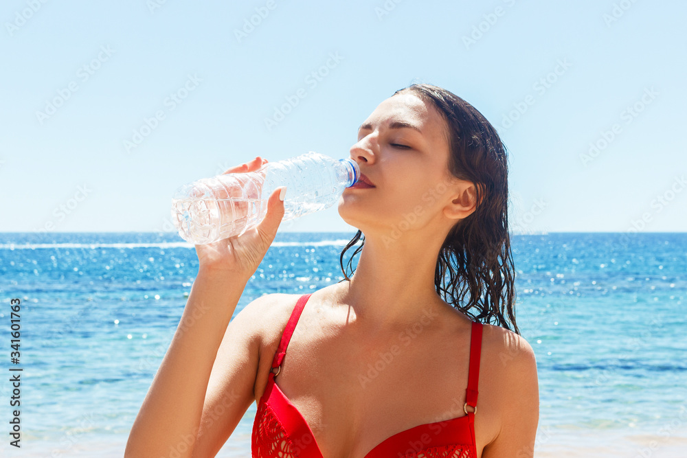 Sporty young woman is drinking water from the bottle after training at the beach. Active healthy life concept Sporty young woman is drinking water from the bottle after training at the beach. Active healthy life concept
