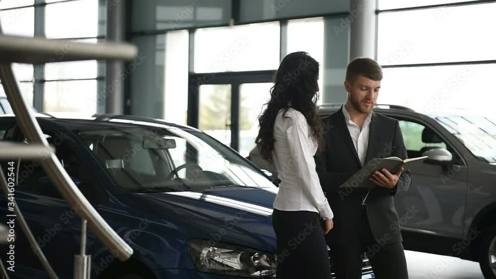 In good mood. Female customer and modern stylish bearded businessman in the automobile saloon. In good mood. Female customer and modern stylish bearded businessman in the automobile saloon.