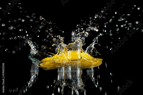 A whole lemon falls into the water on a black background of frozen movement.