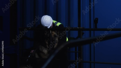 An alert guard dog sits beside a sleeping worker on nightshift at a shipping container yard. photo