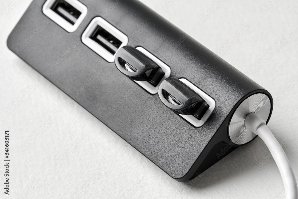 Black portable USB hub for four connections with usb flash drives on a white background. Bus povered. Closeup, selective focus Black portable USB hub for four connections with usb flash drives on a white background. Bus povered. Closeup, selective focus