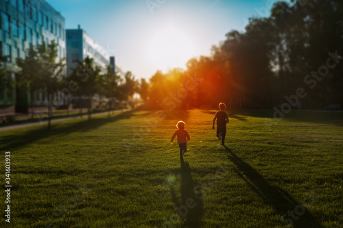 Fototapeta Naklejka Na Ścianę i Meble -  happy little boy and girl run at sunset nature, kids have fun