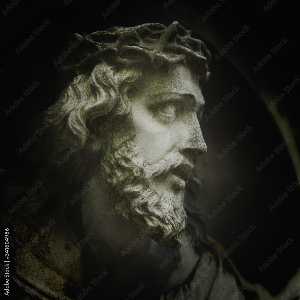 Jesus Christ in a crown of thorns. Fragment of ancient stone statue.