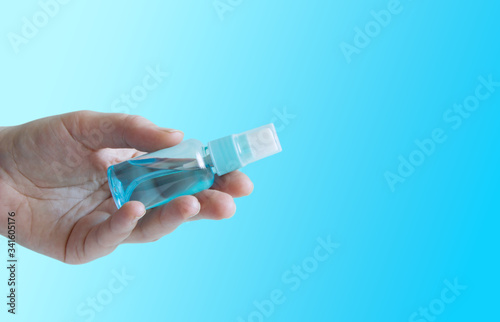 Human hand giving antiseptic spray for disinfection .Prevent infection coronavirus COVID-19. Female hand applying alcohol spray on blue background