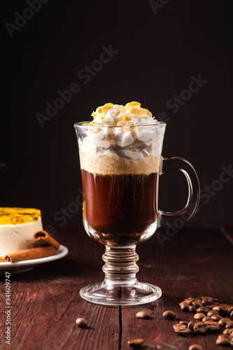 coffee cocktail based on espresso, irish whiskey and whipped cream in a transparent glass on a brown wooden table. Alcoholic coffee cocktail. Alcohol drink