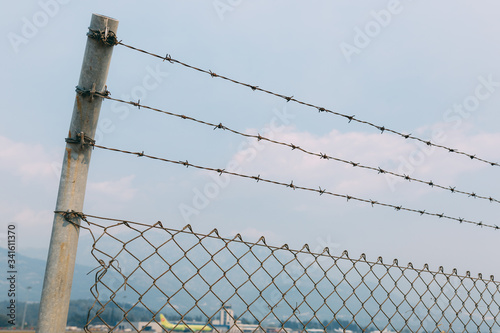 A fence with barbed wire against the sky, a fence with a mesh slave