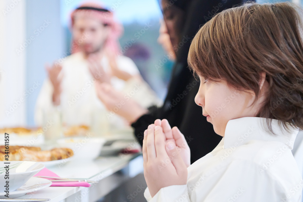 little muslim boy praying with family before iftar dinner little muslim boy praying with family before iftar dinner