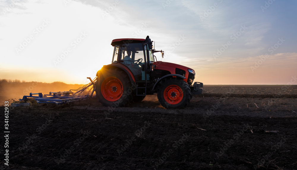 Obraz premium Tractor is preparing the land at dusk