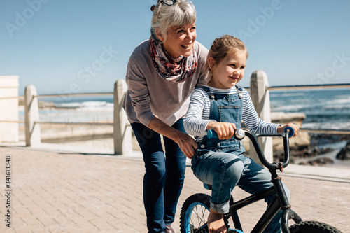 Senior woman helping her granddaughter learn to ride a bicycle