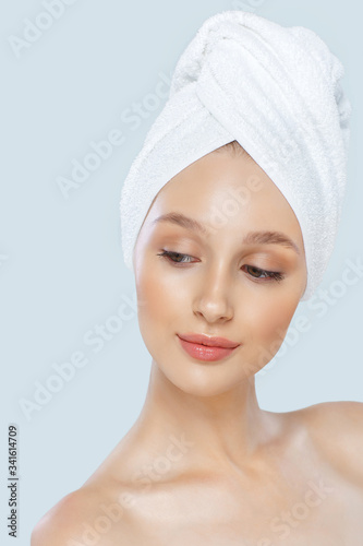 Beautiful woman in a white towel on a head. Isolated on a gray background