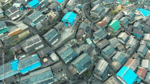 Aerial view of the largest Gurung village Bhujung on a slope of a hill. Early Morning tight shot from a drone flying over the village in Lamjung, Gandaki, Nepal. photo