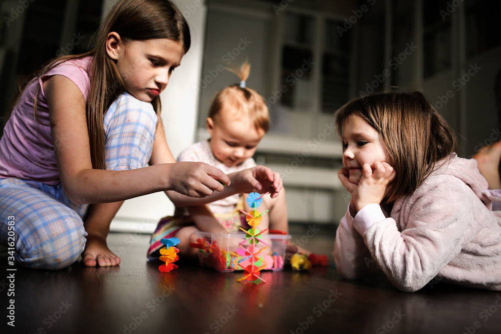 Naklejka premium siblings play together with toys on dark floor