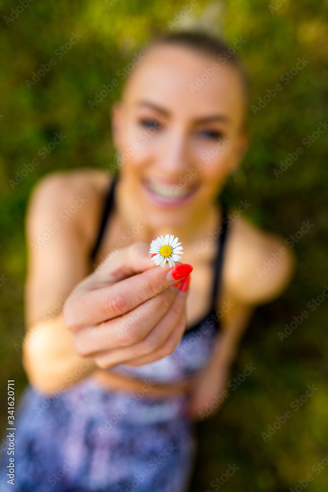 Sexy sportliche Frau genießt die Sonne im grünen Gras mit Gänseblümchen Sexy sportliche Frau genießt die Sonne im grünen Gras mit Gänseblümchen