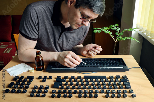 Photos During isolation, a person is busy cleaning the inside of a computer keyboard