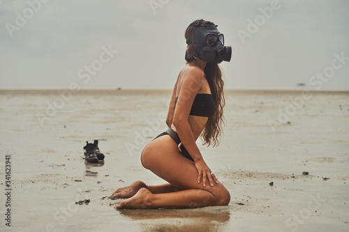 Obraz na płótnie A woman with a pretty body wears a gas mask and relax on the beach w salonie