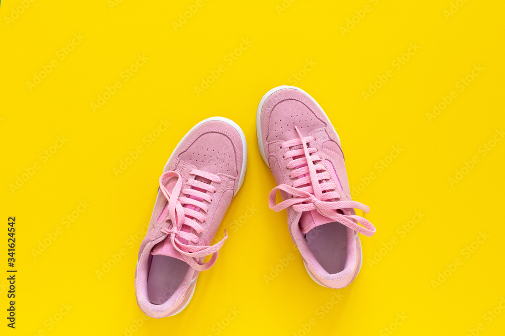 Pink nubuck sneakers isolated on a yellow background, seasonal shoes for walking and sports, top view Pink nubuck sneakers isolated on a yellow background, seasonal shoes for walking and sports, top view