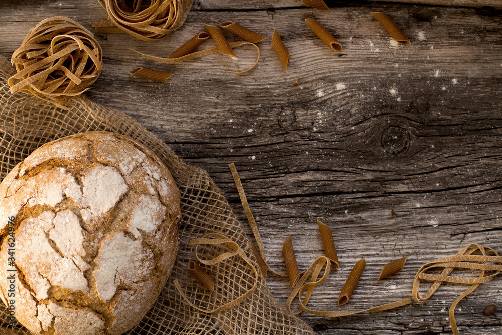 pasta and bread on a wooden table - homemade pasta lying on a wooden, rustic table.
