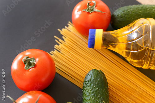 Various products. Spaghetti, pasta, tomatoes, cucumbers and vegetable sunflower oil on a gray background with place for text.