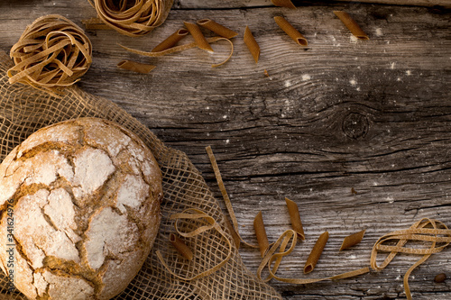 pasta and bread on a wooden table - homemade pasta lying on a wooden, rustic table.