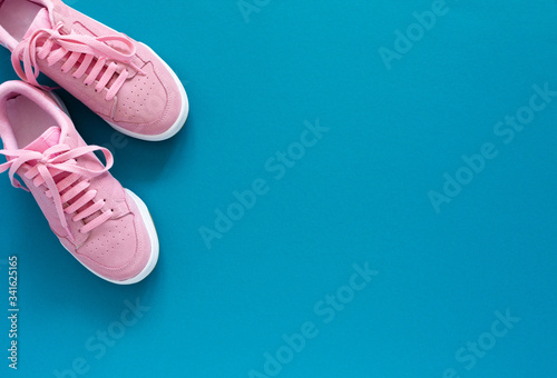 Pink nubuck sneakers isolated on a turquoise blue background, seasonal shoes for walking and sports, top view