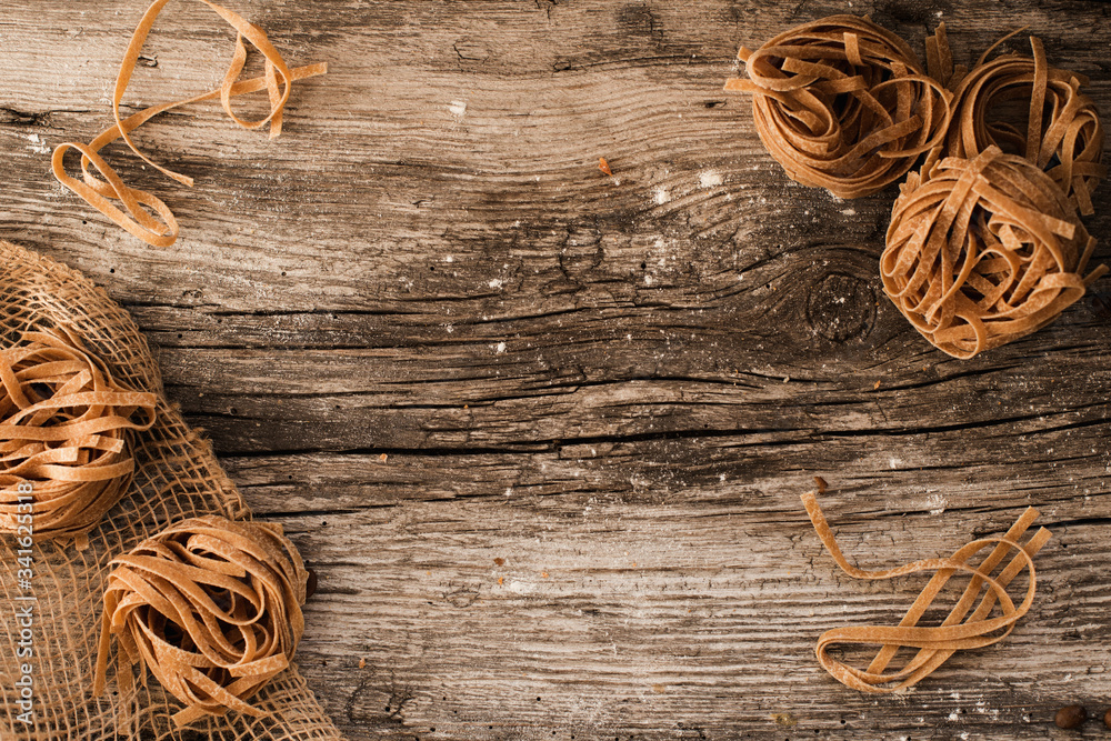 pasta on a wooden table - homemade pasta lying on a wooden, rustic table.