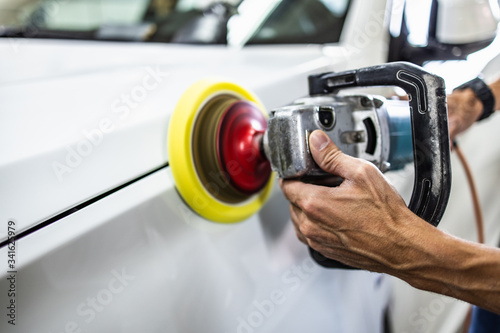 Car detailing - Hands with orbital polisher in auto repair shop. Selective focus.