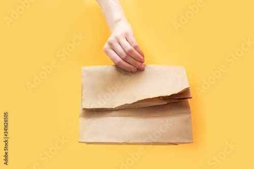 Courier keep craft paper bag with food isolated on yellow background Studio service quarantine pandemic coronavirus virus 2019-ncov concept photo