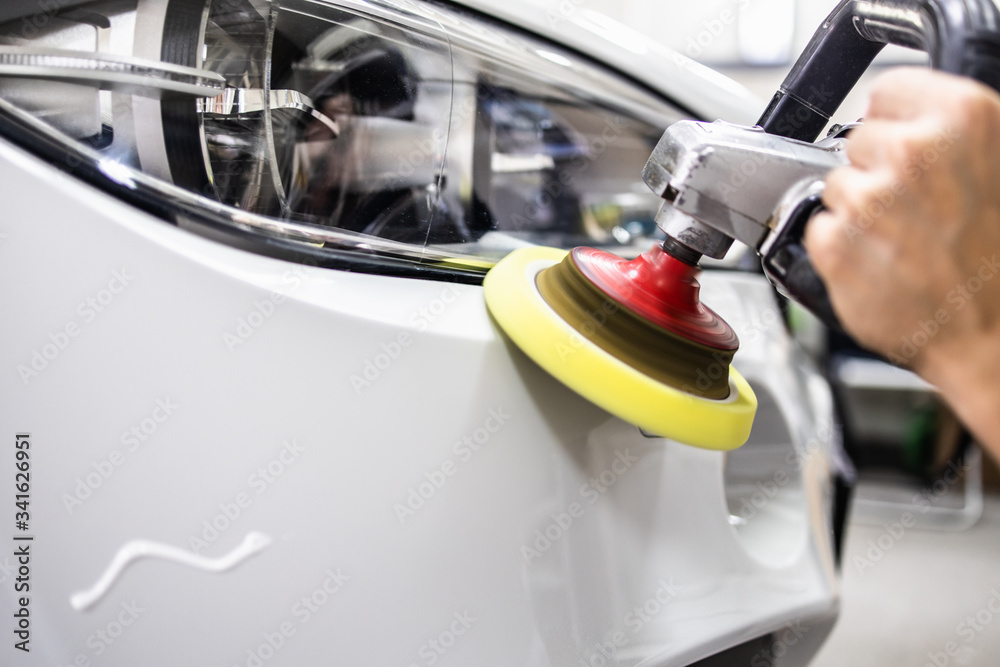 Car detailing - Hands with orbital polisher in auto repair shop. Selective focus. Car detailing - Hands with orbital polisher in auto repair shop. Selective focus.