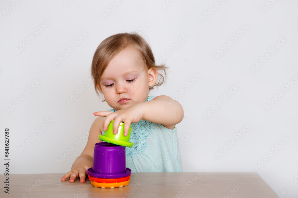 little girl plays at home with a pyramid of colored jars little girl plays at home with a pyramid of colored jars