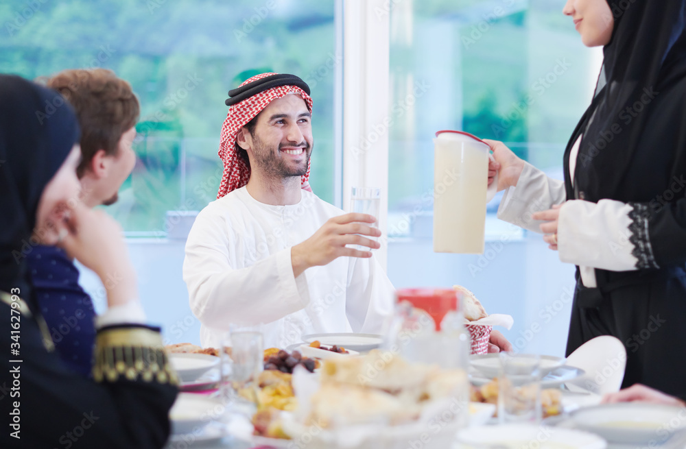 Muslim family having Iftar dinner drinking water to break feast