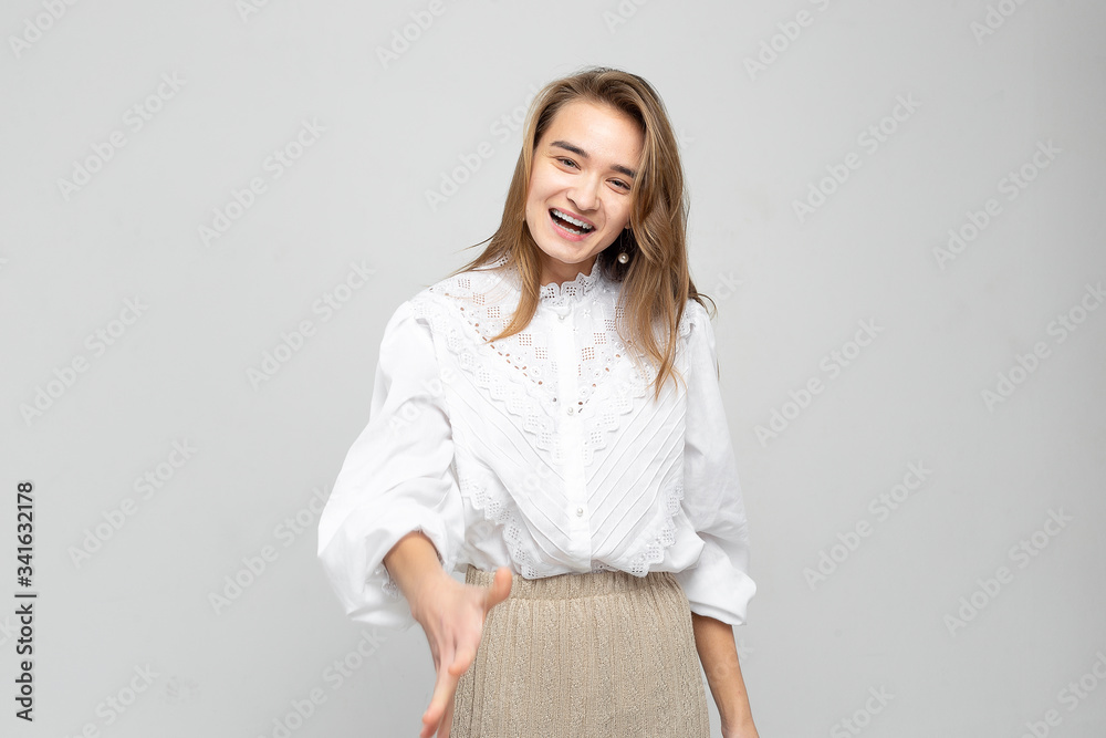 Very emotional woman laughs while tearing her stomach and holds her hands covering her face. Portrait of a beautiful woman on a white-gray background Very emotional woman laughs while tearing her stomach and holds her hands covering her face. Portrait of a beautiful woman on a white-gray background