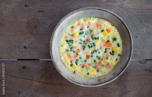 Steamed egg with vegetable in the bowl on the old wooden table.