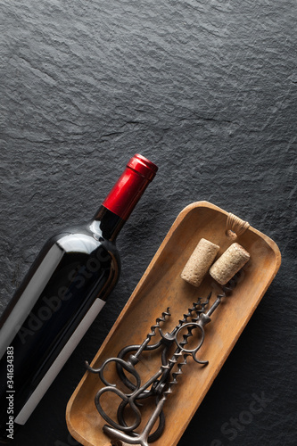 A bottle of wine next to corkscrews.A bottle of wine next to corkscrews.A bottle of wine next to corkscrews