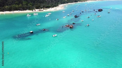 Aerial Drone Footage Pans Over Luxury Boats And People Snorkeling Over Ship Wreck Reefs In Crystal Clear Blue Turquoise Ocean On The Beach Coastline Of A Sand Island On A Sunny Day. photo