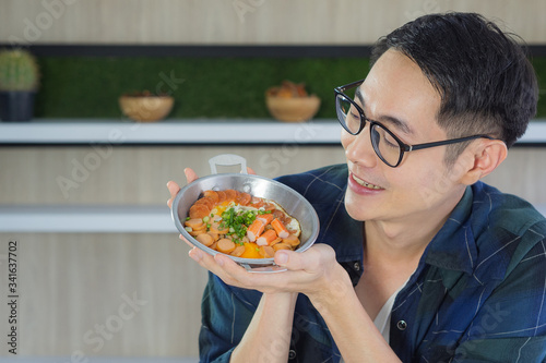 Young man looking at food while sitting at home. The fried egg with colorful toppings served on pan  panned egg . Simple food for breakfast. Healthy foods concept