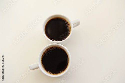 Black coffee in two white cups in the shape of number eight on white background