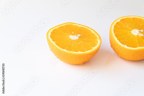 Two halves of fresh orange with drops of water on a white background