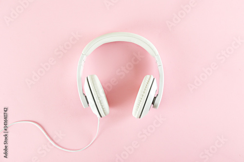 Minimalistic top view composition with white headphones on bright paper textured background with a lot of copy space for your text. Close up, flat lay.