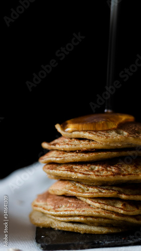 OAT PANCAKES WITH SYRUP ON A BLACK BACKGROUND
