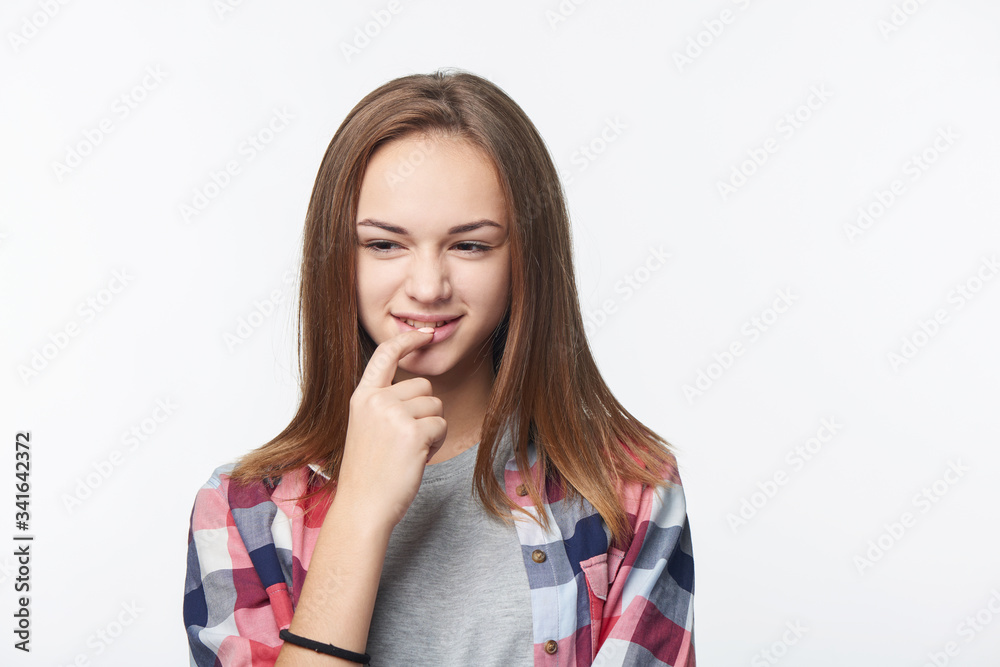 Sly teen girl thinking biting her finger looking to side Sly teen girl thinking biting her finger looking to side