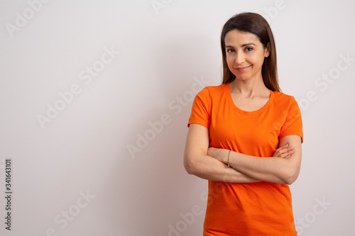 ragazza mora  maglietta arancione con le mani conserte, isolata su sfondo bianco photo