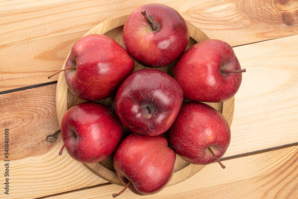 Lot of whole red delicious apple on bamboo plate on wood Lot of whole red delicious apple on bamboo plate on wood