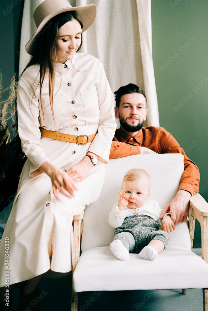 a beautiful young family of three. happy Father and mother hold their little son in their arms. trending colors. the concept of family