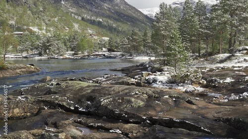 A view of the Gaula river near the Likholefossen waterfall. The river carrying its' turbulent waters to the valley. Pine forest covering mountain foothills and riverbanks.  Fresh snow is everywhere. photo